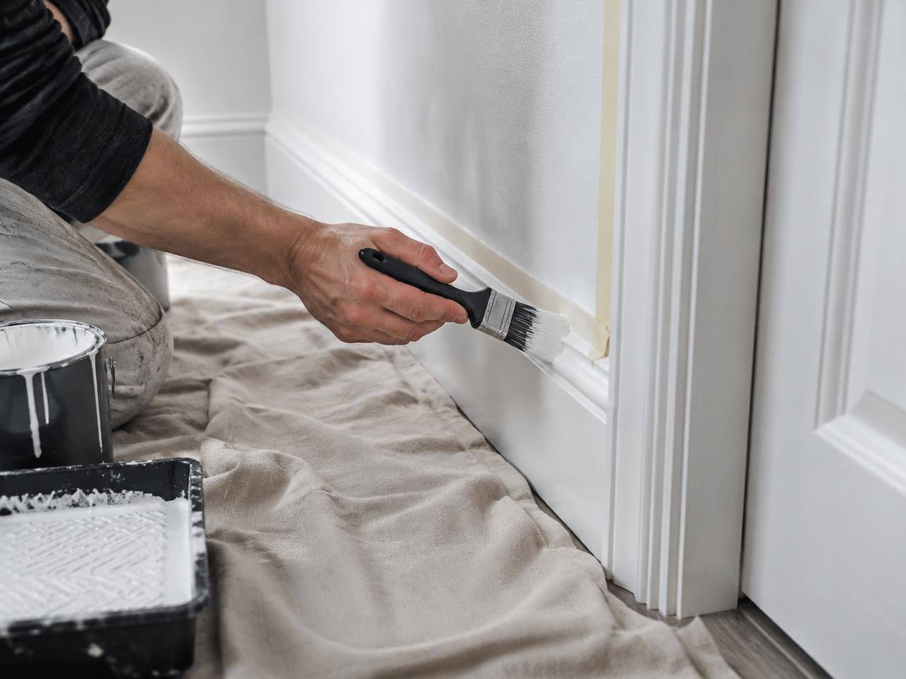 Decorator cutting in paint along a skirting board